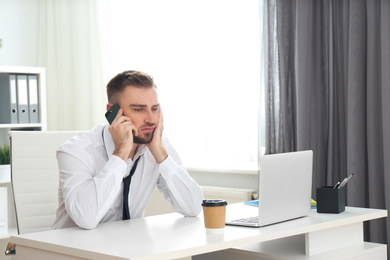 Lazy young man talking on smartphone in office