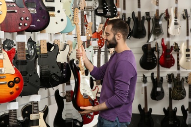 Buyer choosing guitar in modern music store