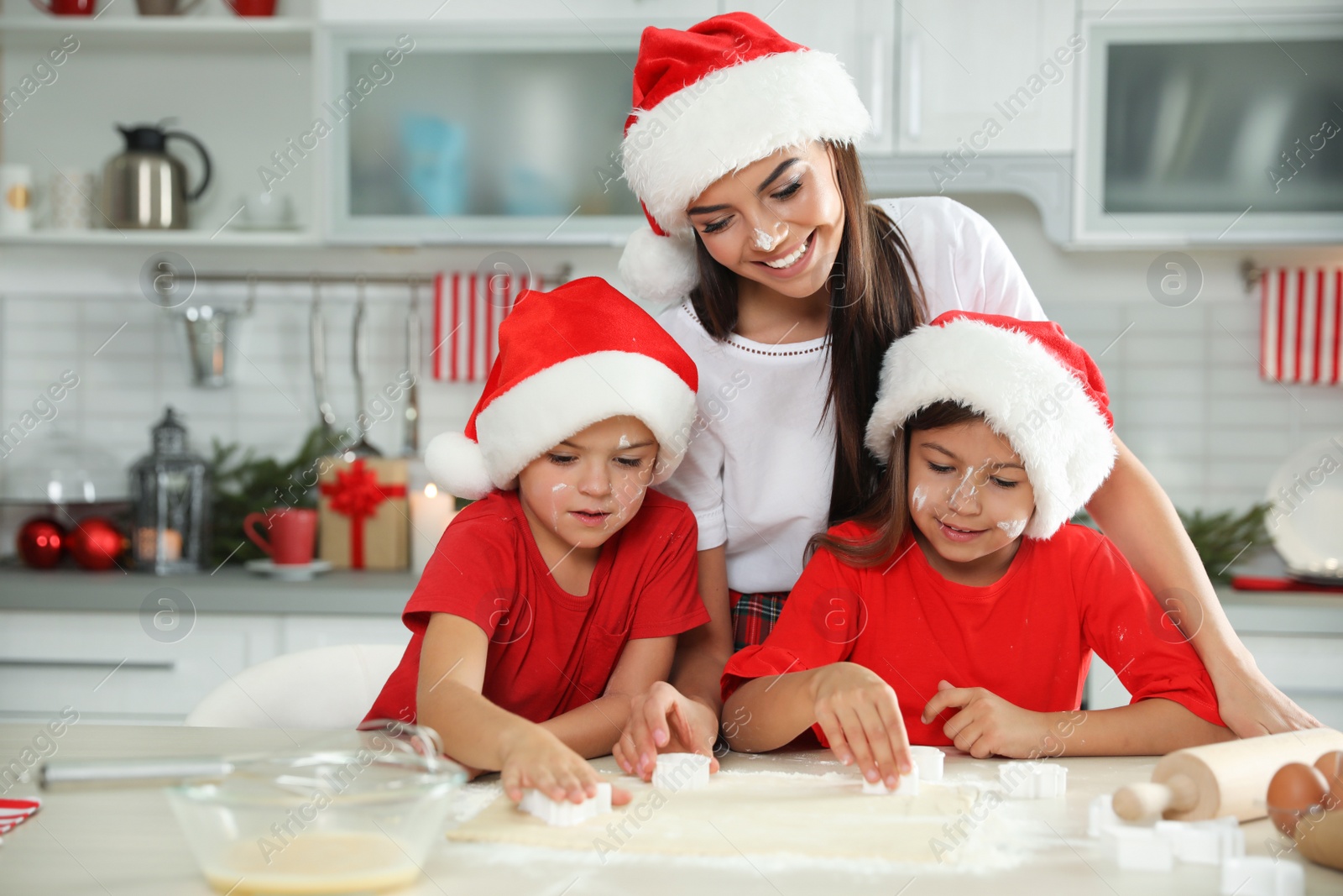 Photo of Happy family with Santa hats cooking in kitchen. Christmas time