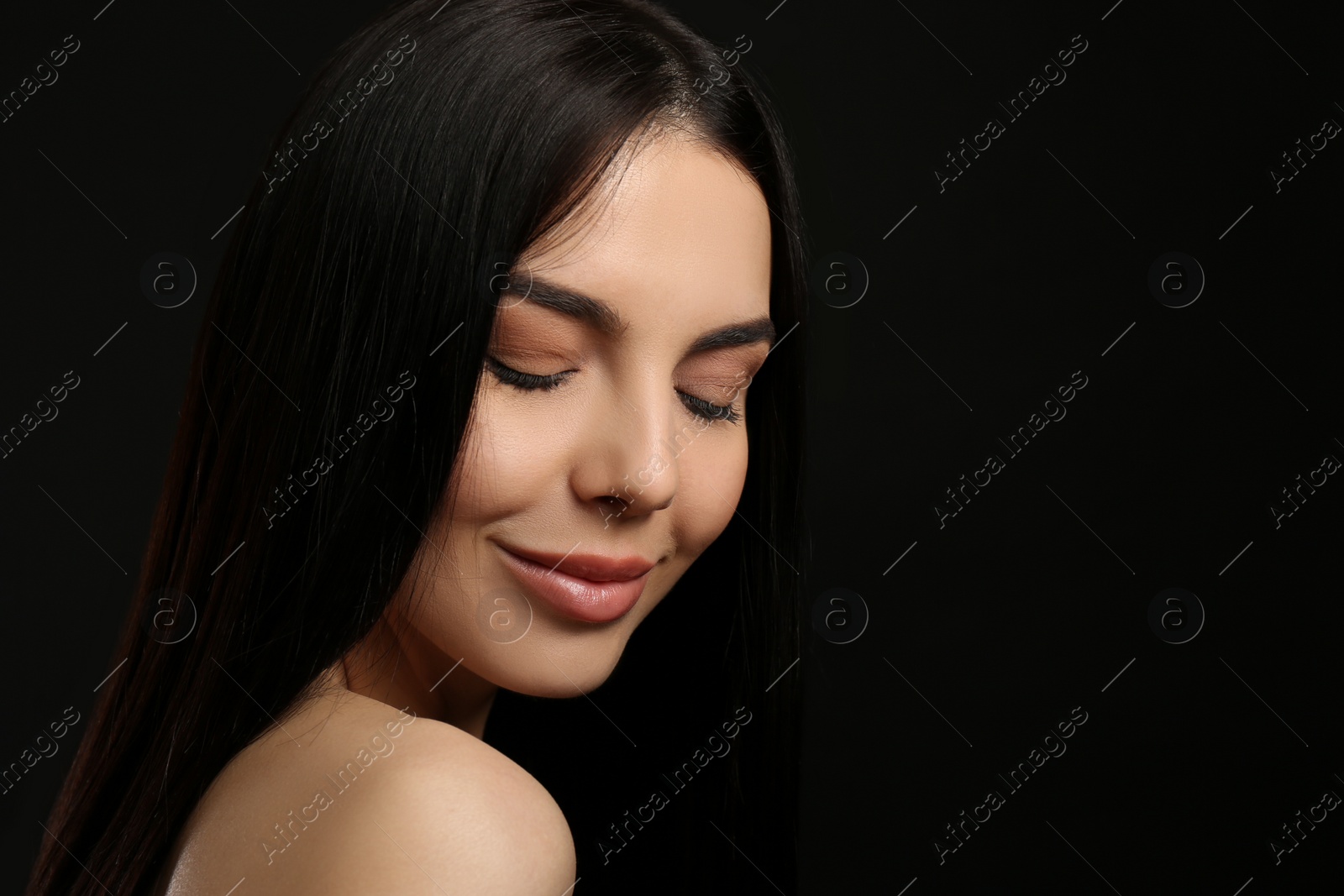 Photo of Portrait of happy young woman with beautiful black hair and charming smile on dark background, space for text