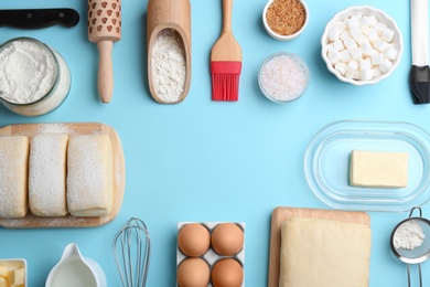 Photo of Frame made with puff pastry dough and ingredients on light blue background, flat lay. Space for text