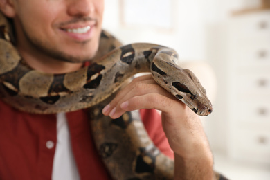 Man with his boa constrictor at home, closeup. Exotic pet