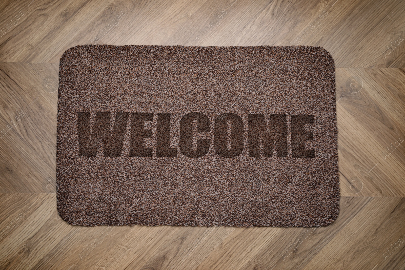 Image of Door mat with word Welcome on wooden floor, top view