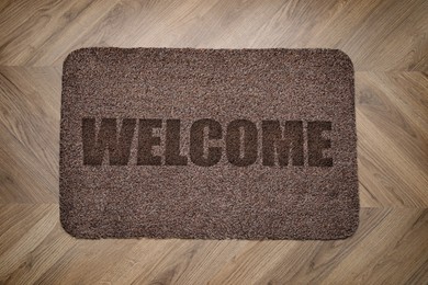 Door mat with word Welcome on wooden floor, top view