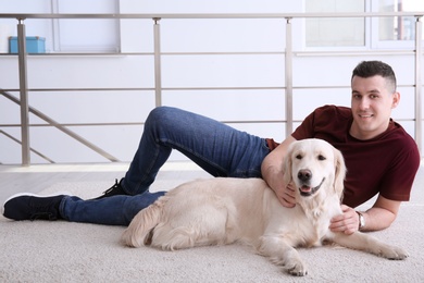 Photo of Handsome man with dog lying on carpet at home