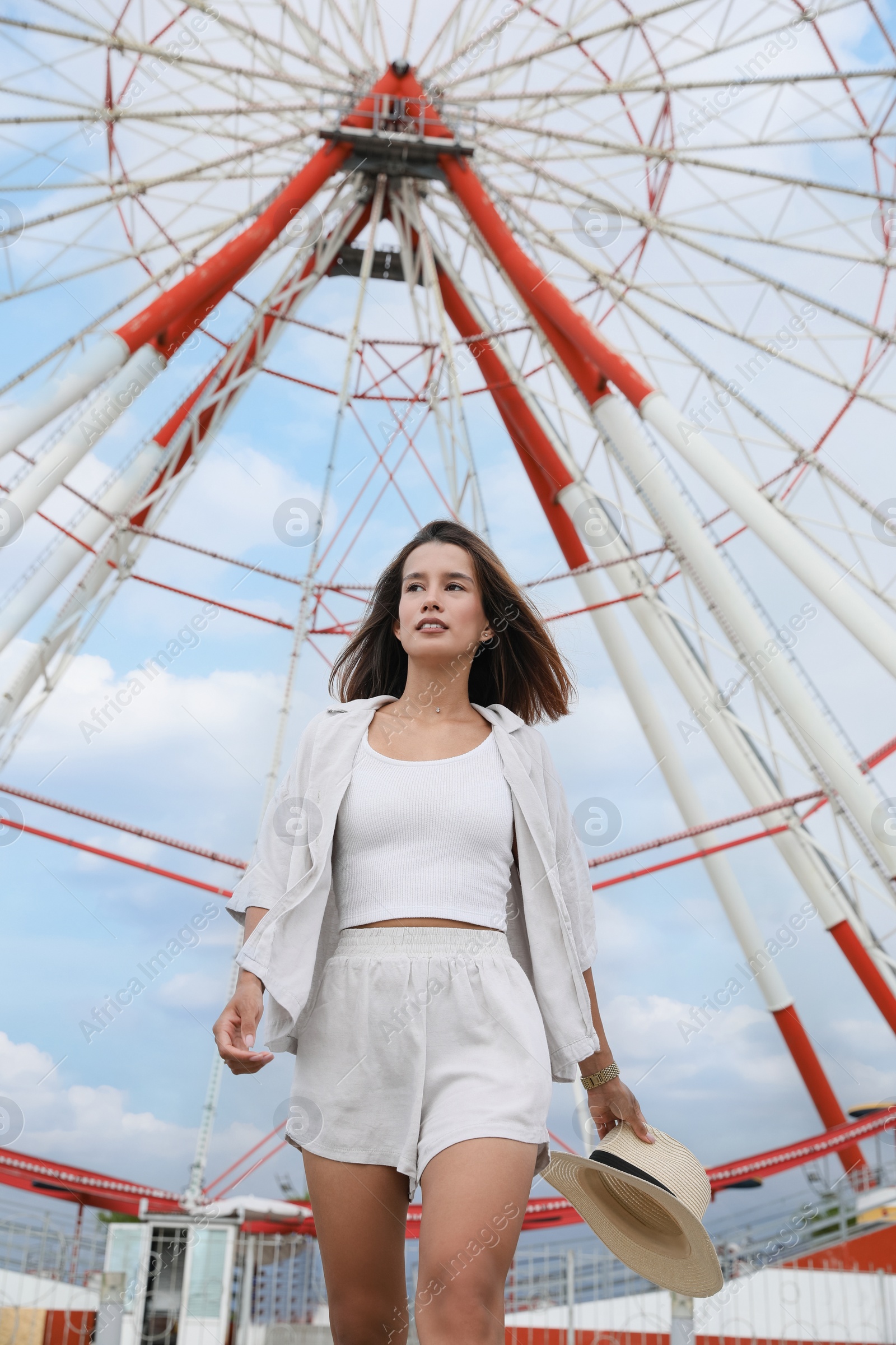 Photo of Beautiful young woman near Ferris wheel outdoors, low angle view