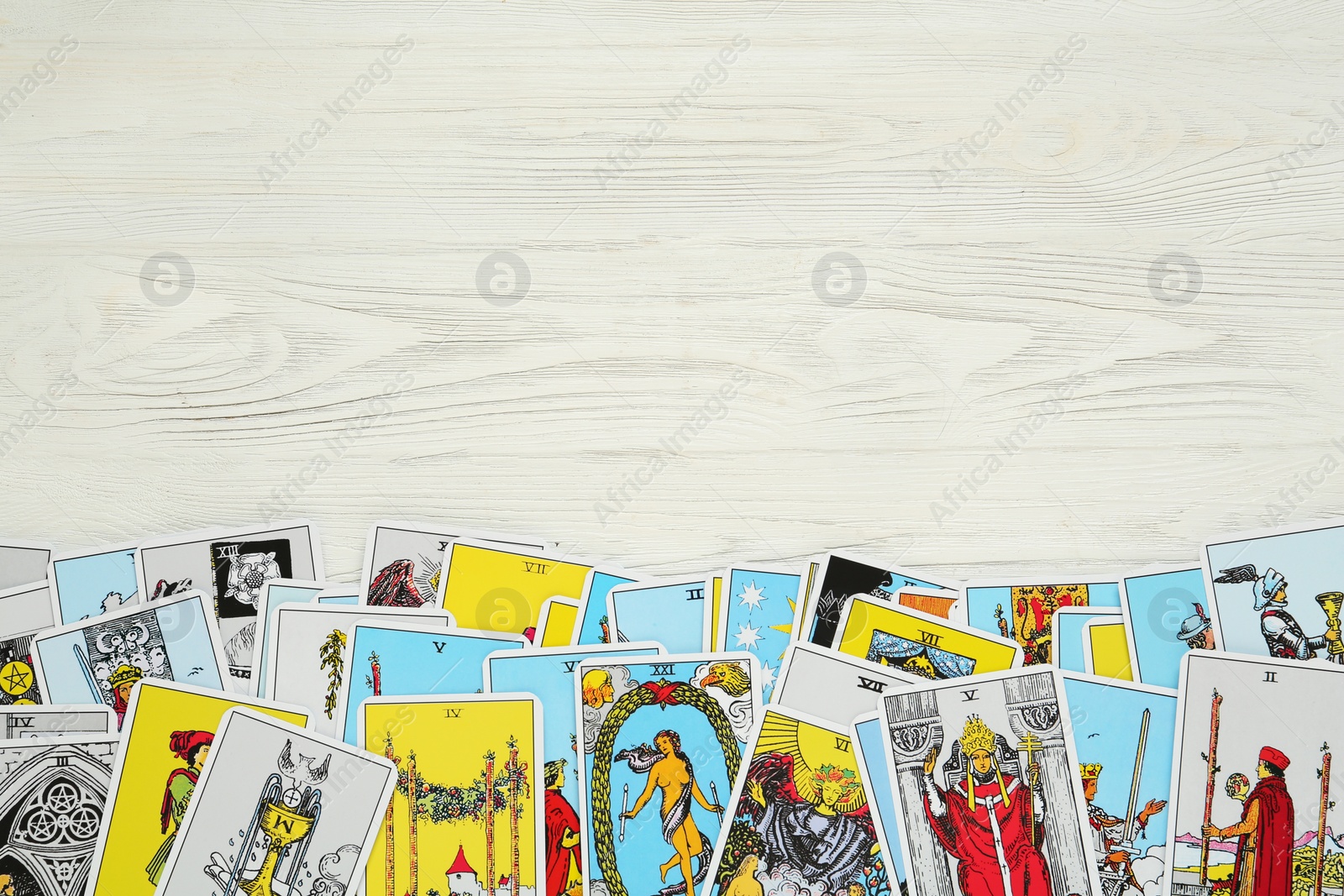 Photo of Tarot cards on white wooden table, top view. Space for text