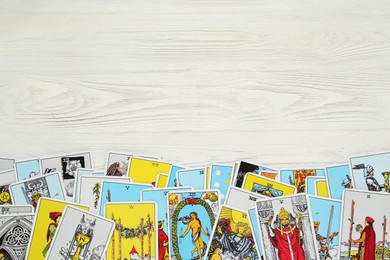 Photo of Tarot cards on white wooden table, top view. Space for text