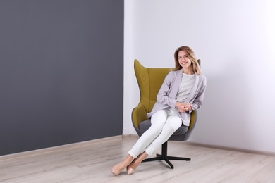 Photo of Young woman sitting in armchair at home. Space for text