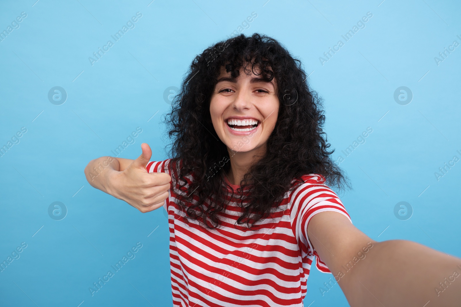 Photo of Beautiful young woman taking selfie on light blue background