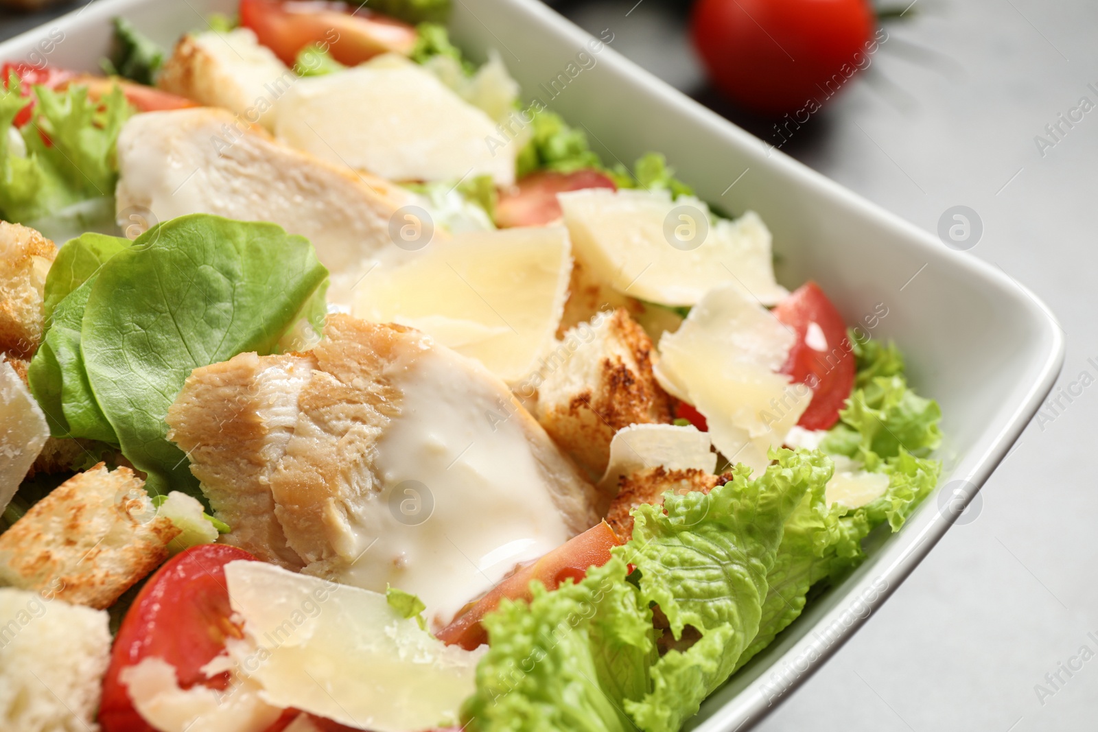 Photo of Delicious fresh Caesar salad in bowl on table, closeup