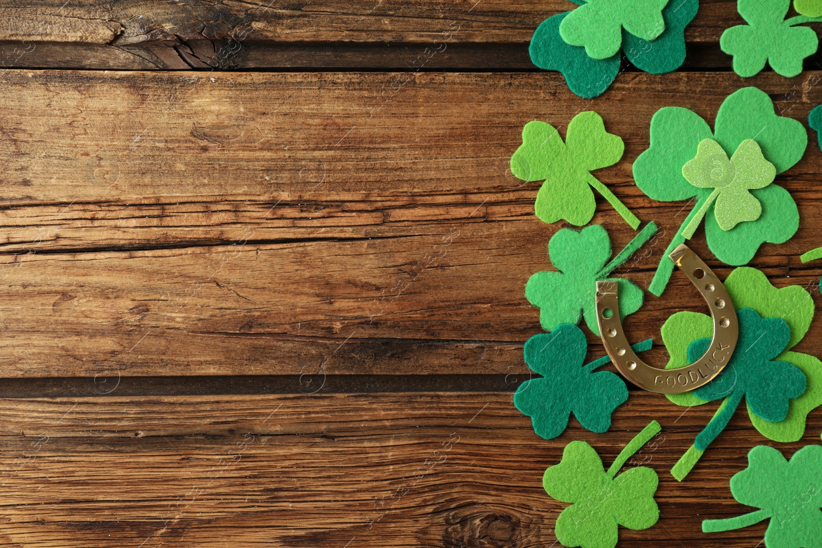 Photo of Flat lay composition with clover leaves and horseshoe on wooden background, space for text. St. Patrick's day