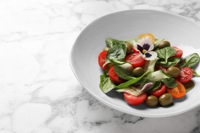Photo of Delicious salad with vegetables and olives on white marble table. Space for text