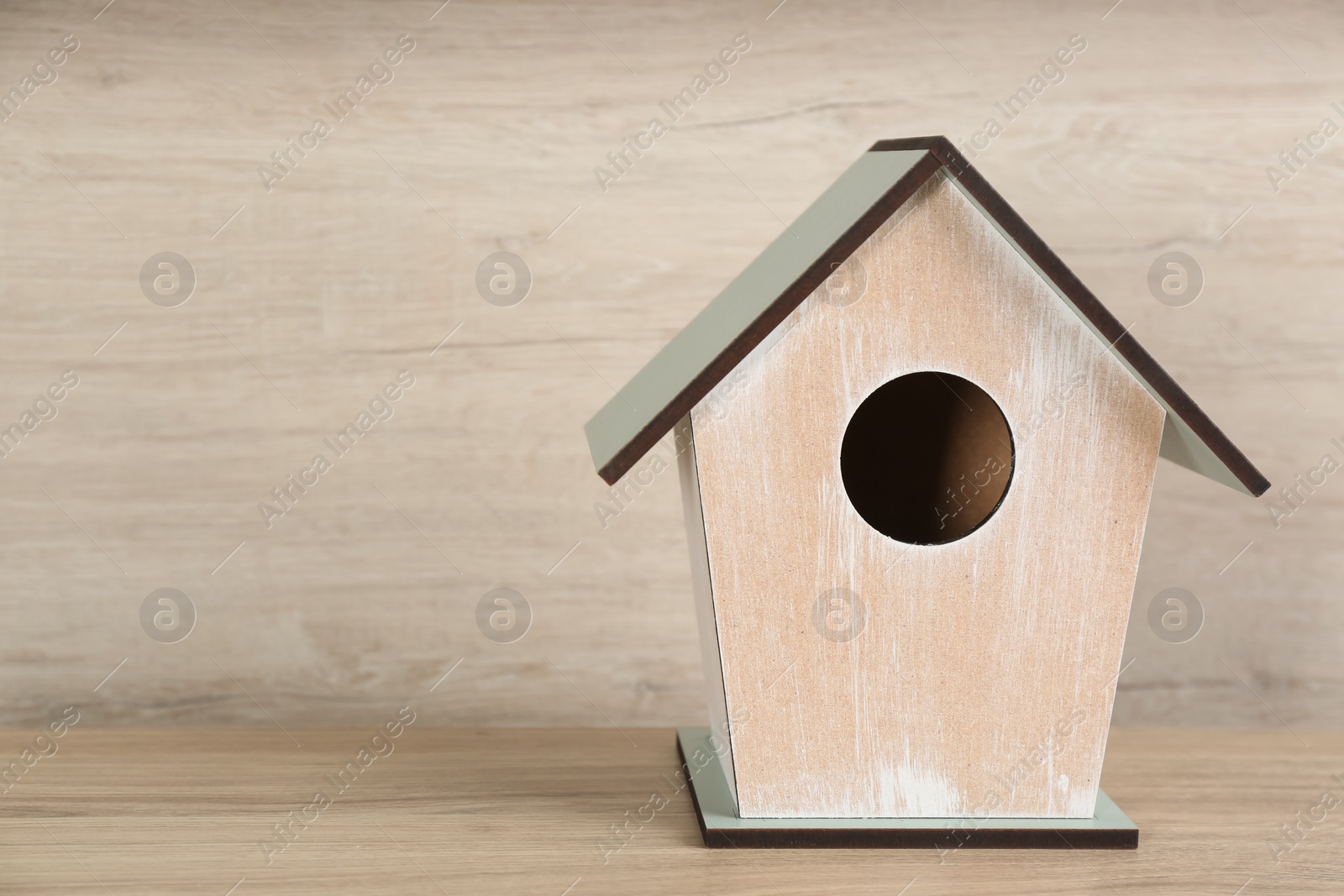 Photo of Beautiful bird house on wooden table, space for text