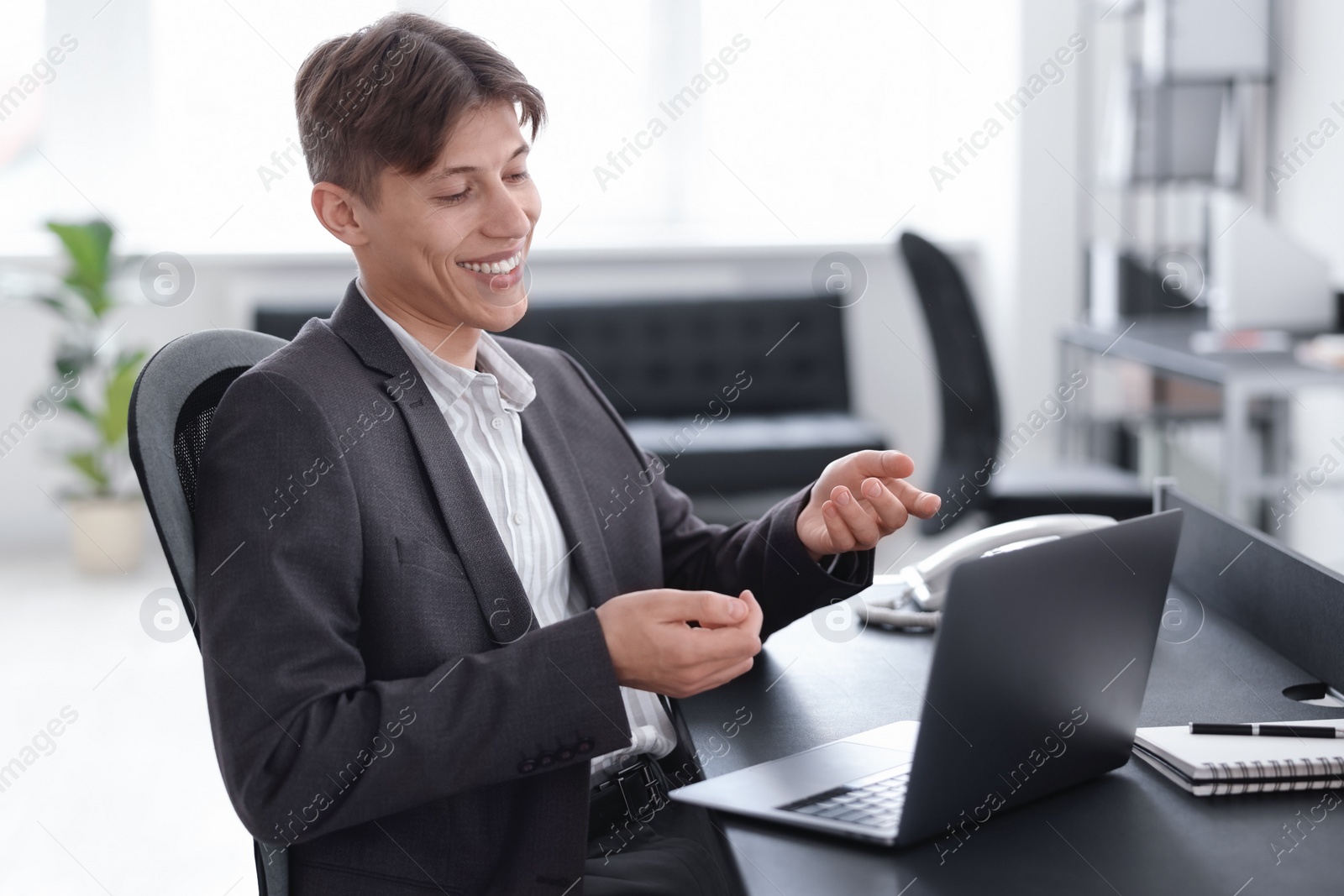 Photo of Man using video chat during webinar at table in office