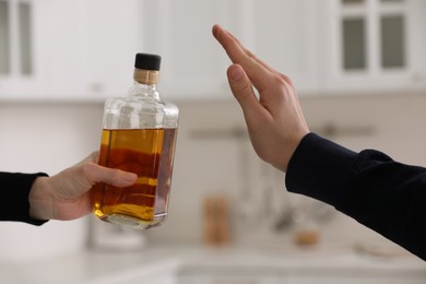 Photo of Man refusing to drink whiskey in kitchen, closeup. Alcohol addiction treatment