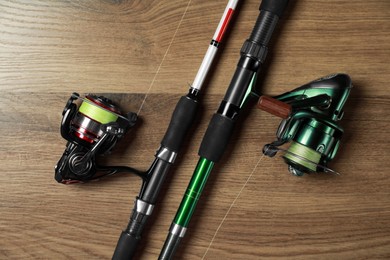 Photo of Fishing rods with spinning reels on wooden background, top view