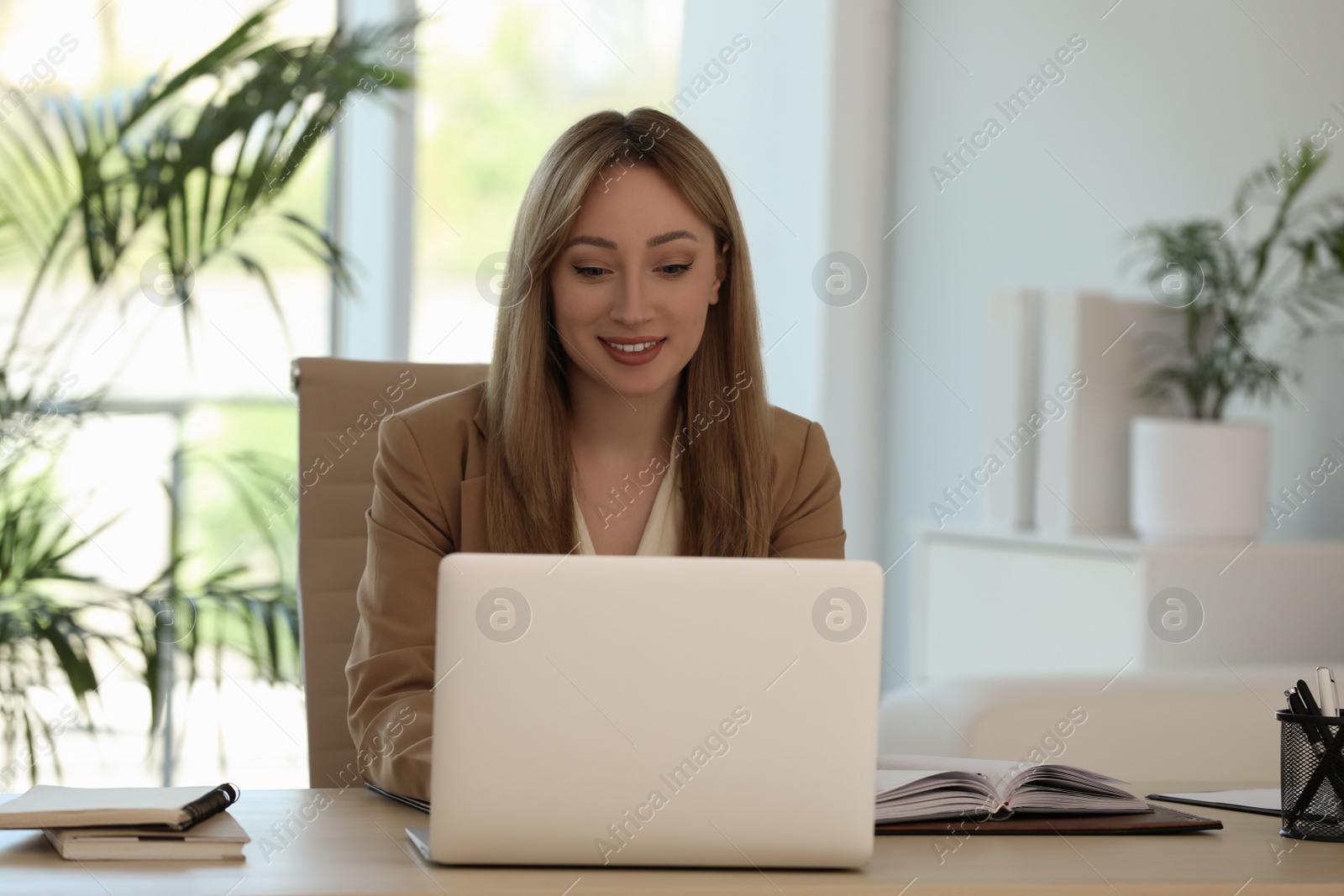 Photo of Secretary working with laptop at wooden table in office