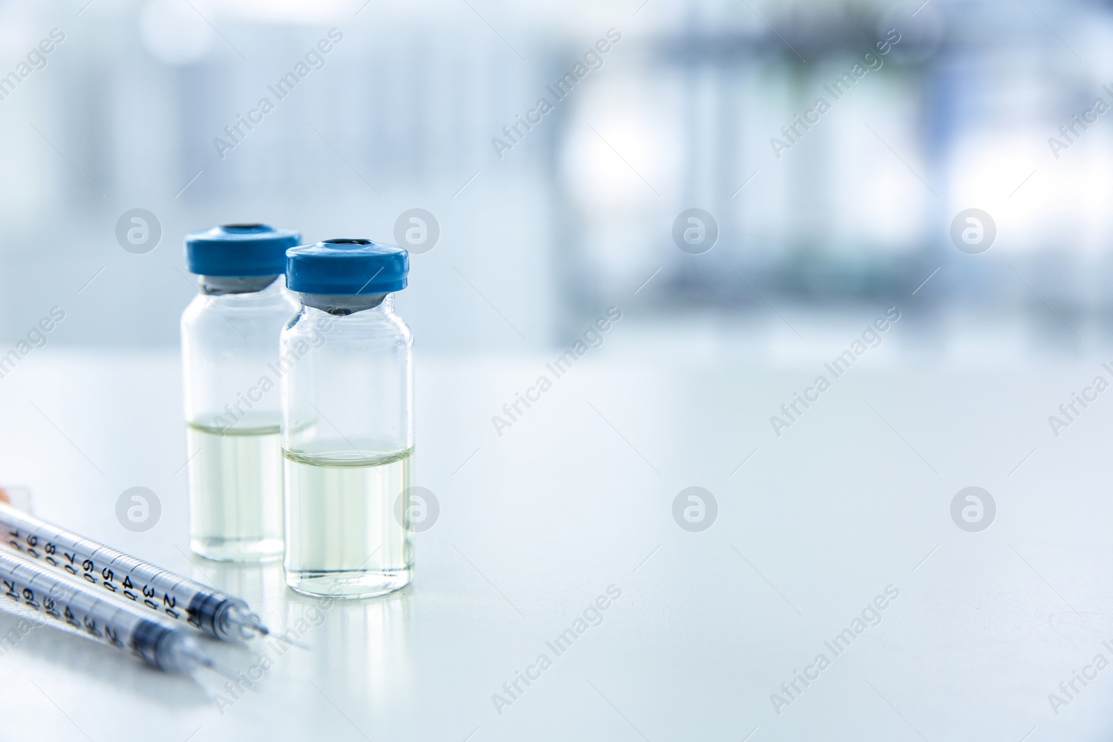 Photo of Vials with medicine and syringes on blurred background. Vaccination concept