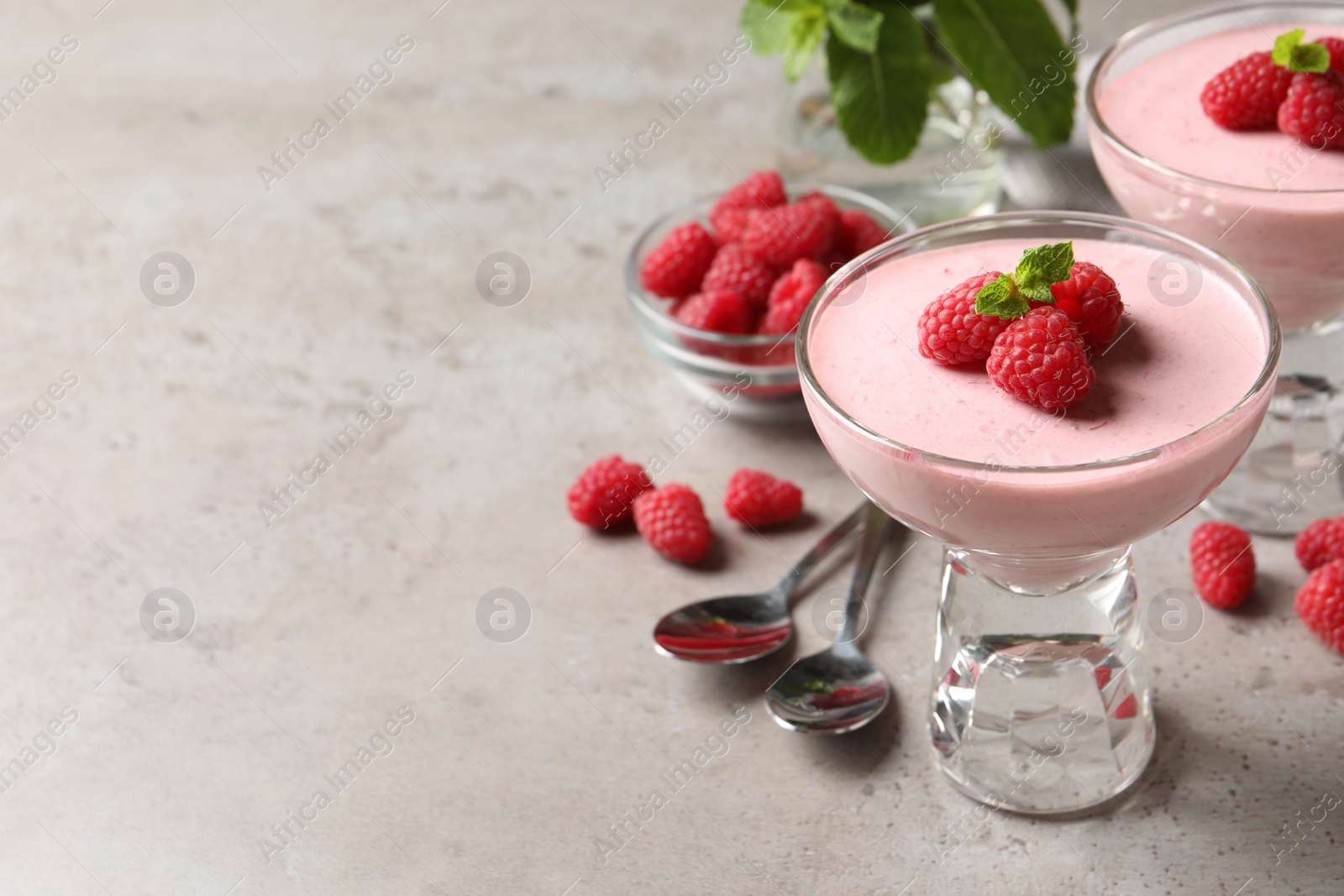 Photo of Delicious raspberry mousse with mint on light grey table, space for text