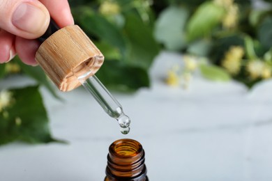 Photo of Woman pouring essential oil from pipette into bottle, closeup. Space for text