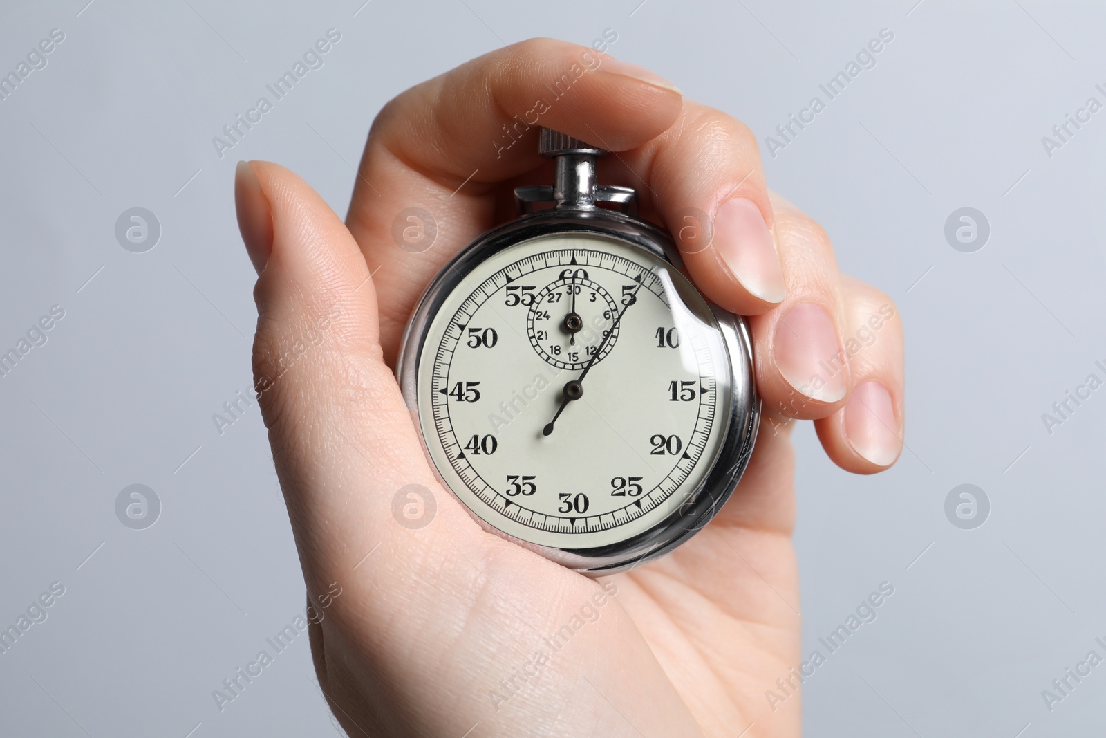 Photo of Woman holding vintage timer on light grey background, closeup