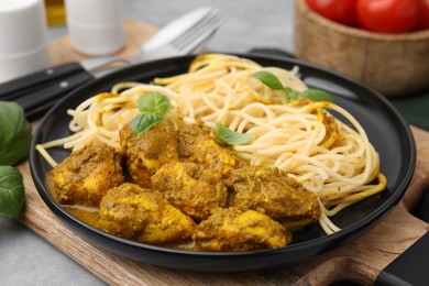 Photo of Delicious pasta and chicken with curry sauce served on table, closeup