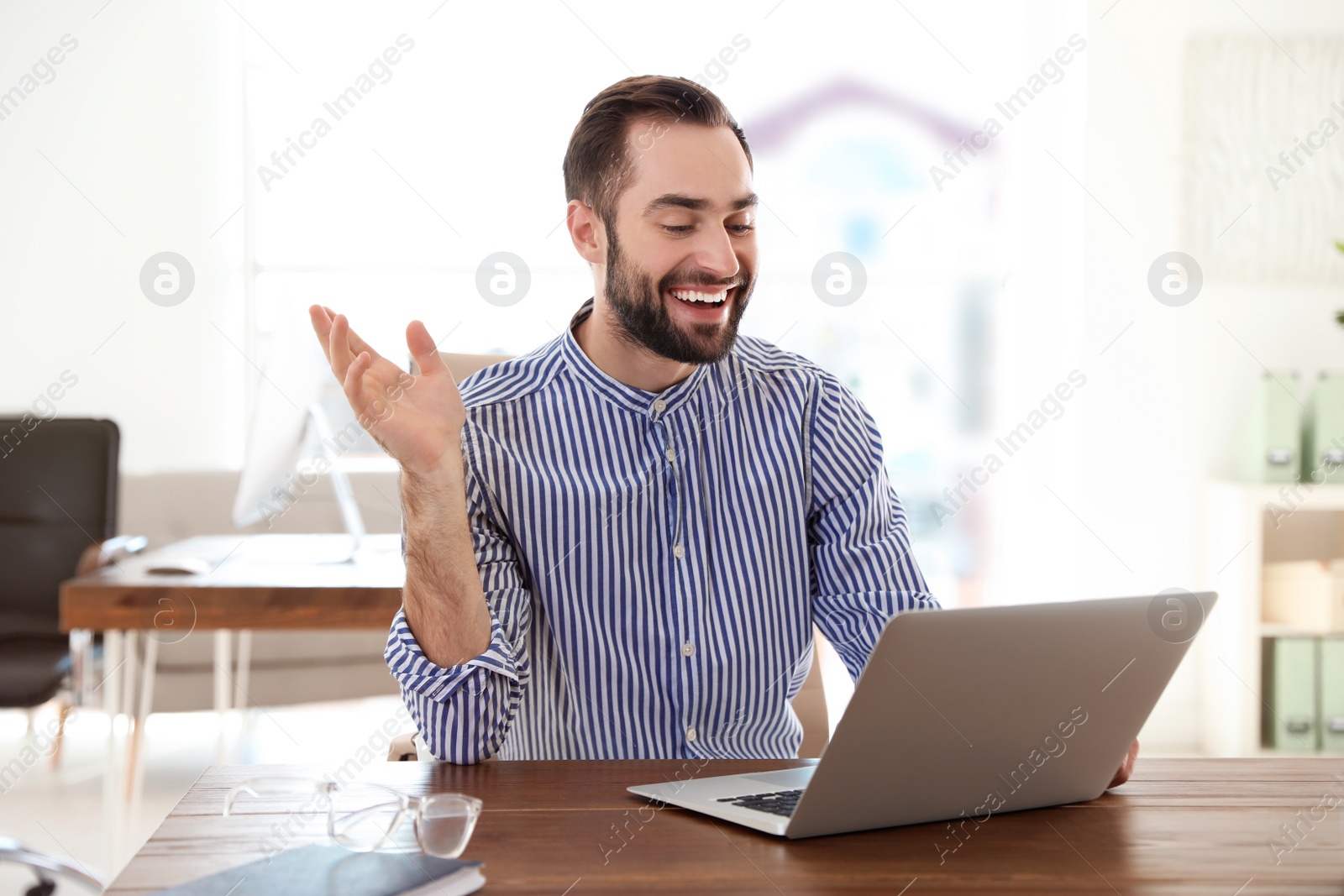 Photo of Young man using video chat on laptop in home office