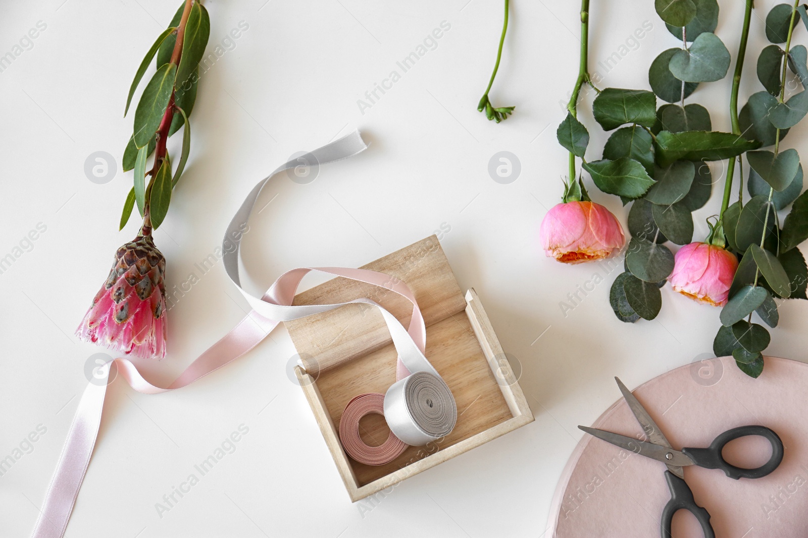 Photo of Professional florist workplace with beautiful flowers, ribbon and scissors, top view