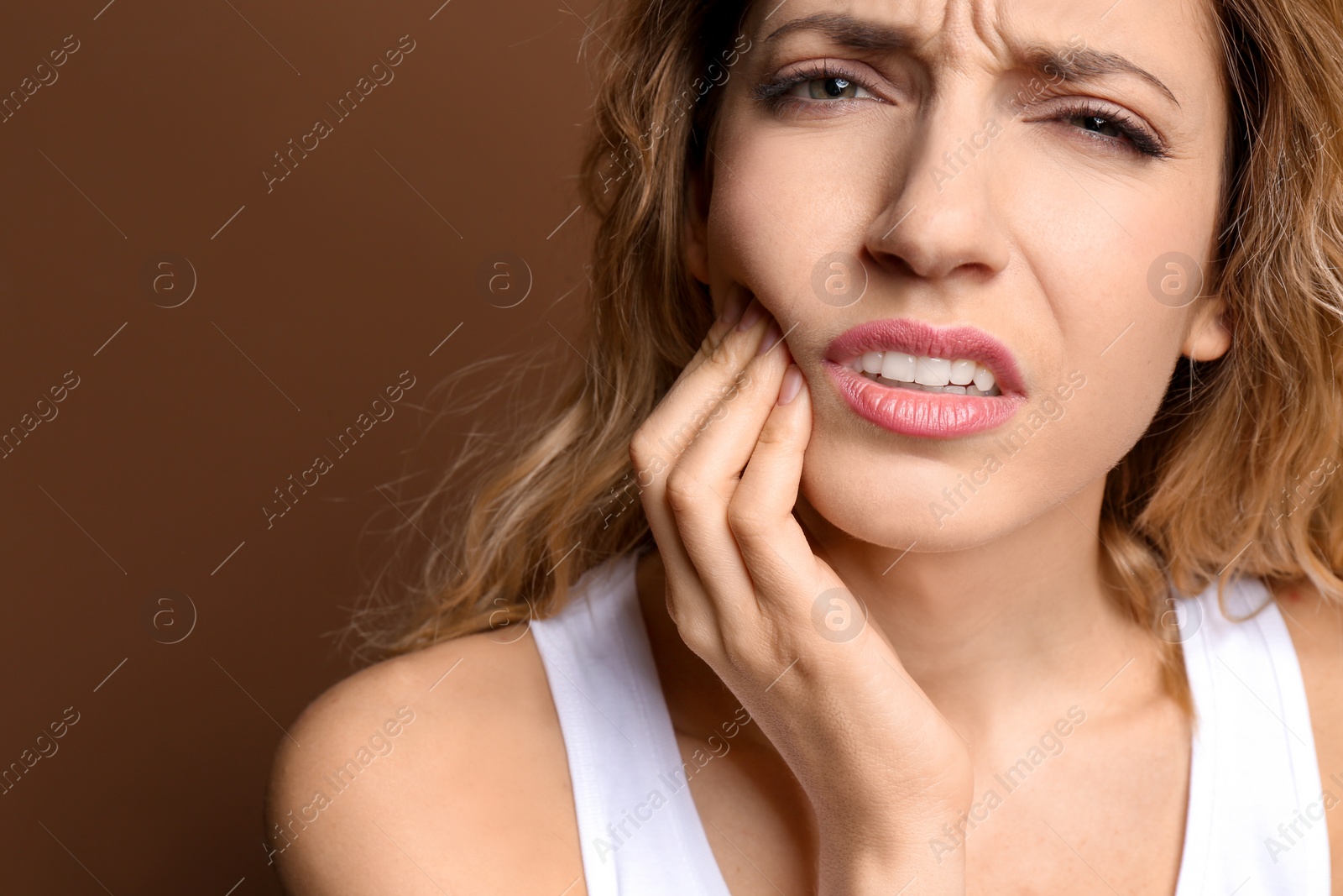 Photo of Young woman suffering from toothache on color background