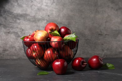 Fresh red apples and leaves on dark grey table