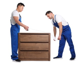 Photo of Workers wrapping chest of drawers in stretch film on white background