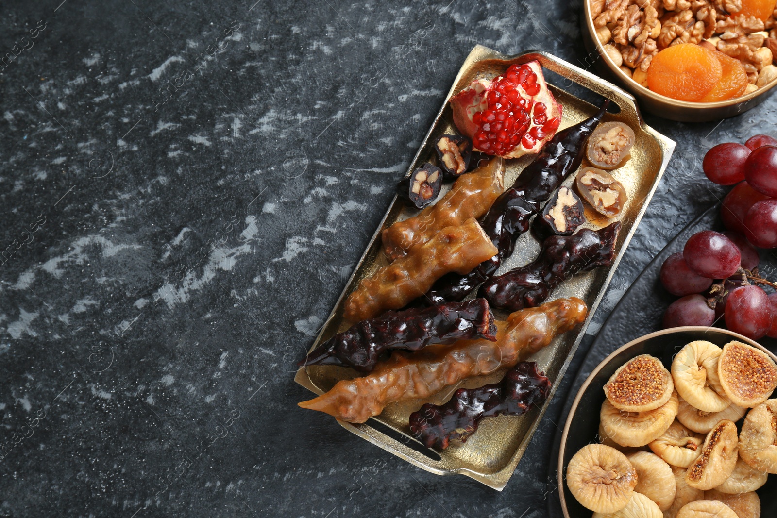 Photo of Delicious sweet churchkhelas and ingredients on textured table, flat lay. Space for text