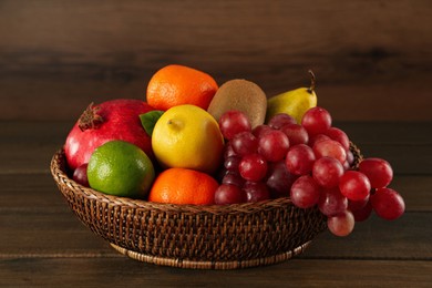 Photo of Fresh ripe fruits in wicker bowl on wooden table