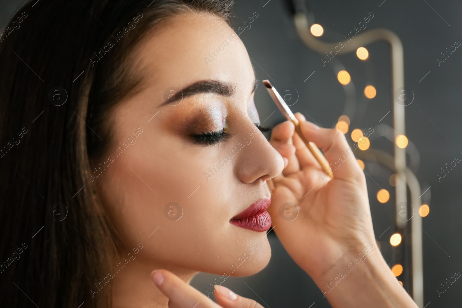 Photo of Professional visage artist applying makeup on woman's face in salon, closeup