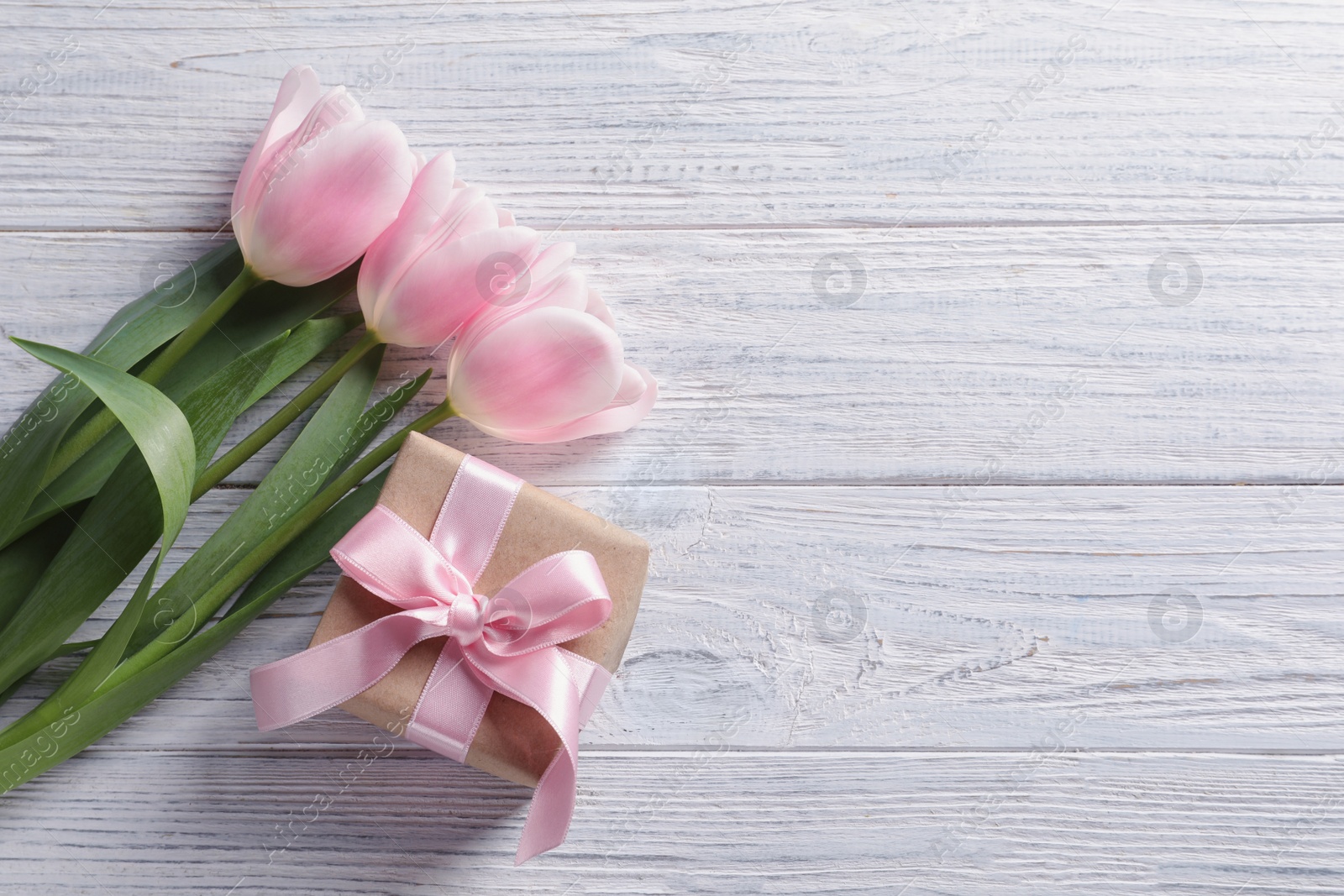 Photo of Beautiful tulips and gift box for Mother's Day on wooden background, top view