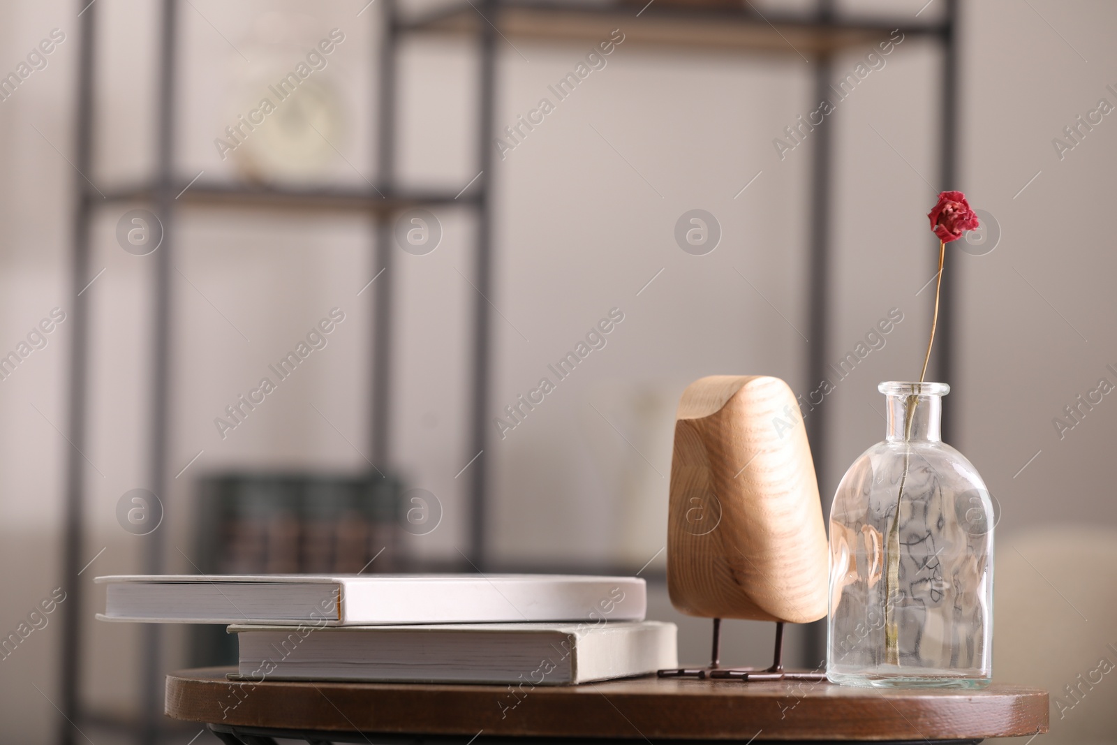 Photo of Vase with dried flower, books and wooden bird on table in room, space for text