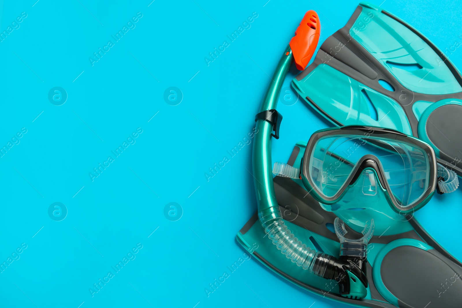 Photo of Pair of turquoise flippers and mask on light blue background, flat lay. Space for text