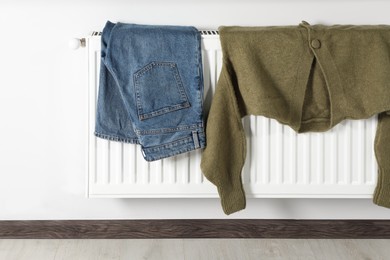 Jeans and cardigan on heating radiator indoors