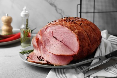 Photo of Delicious baked ham, carving fork and knife on light grey table
