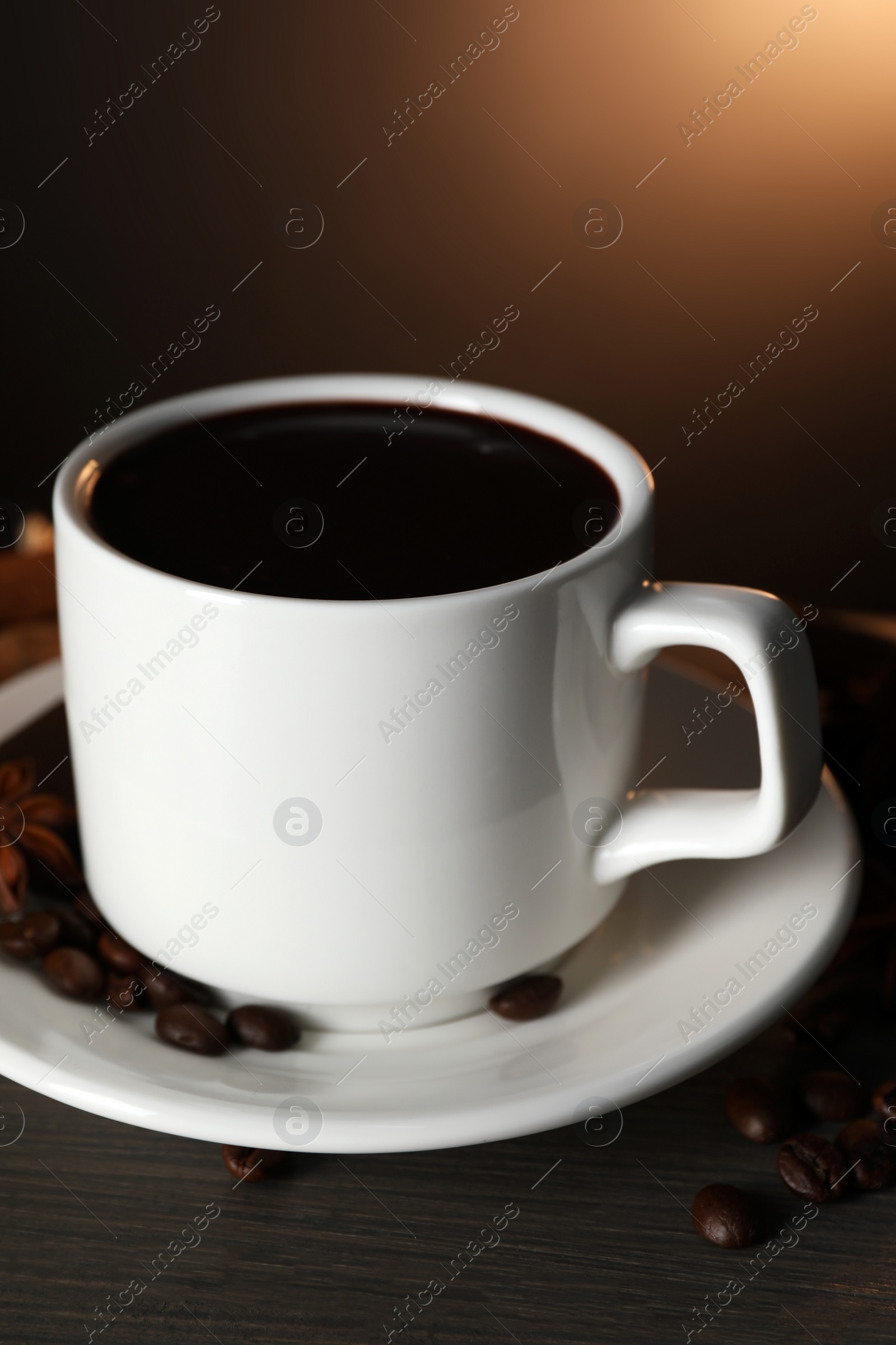 Photo of Cup of delicious hot chocolate and scattered coffee beans on wooden table