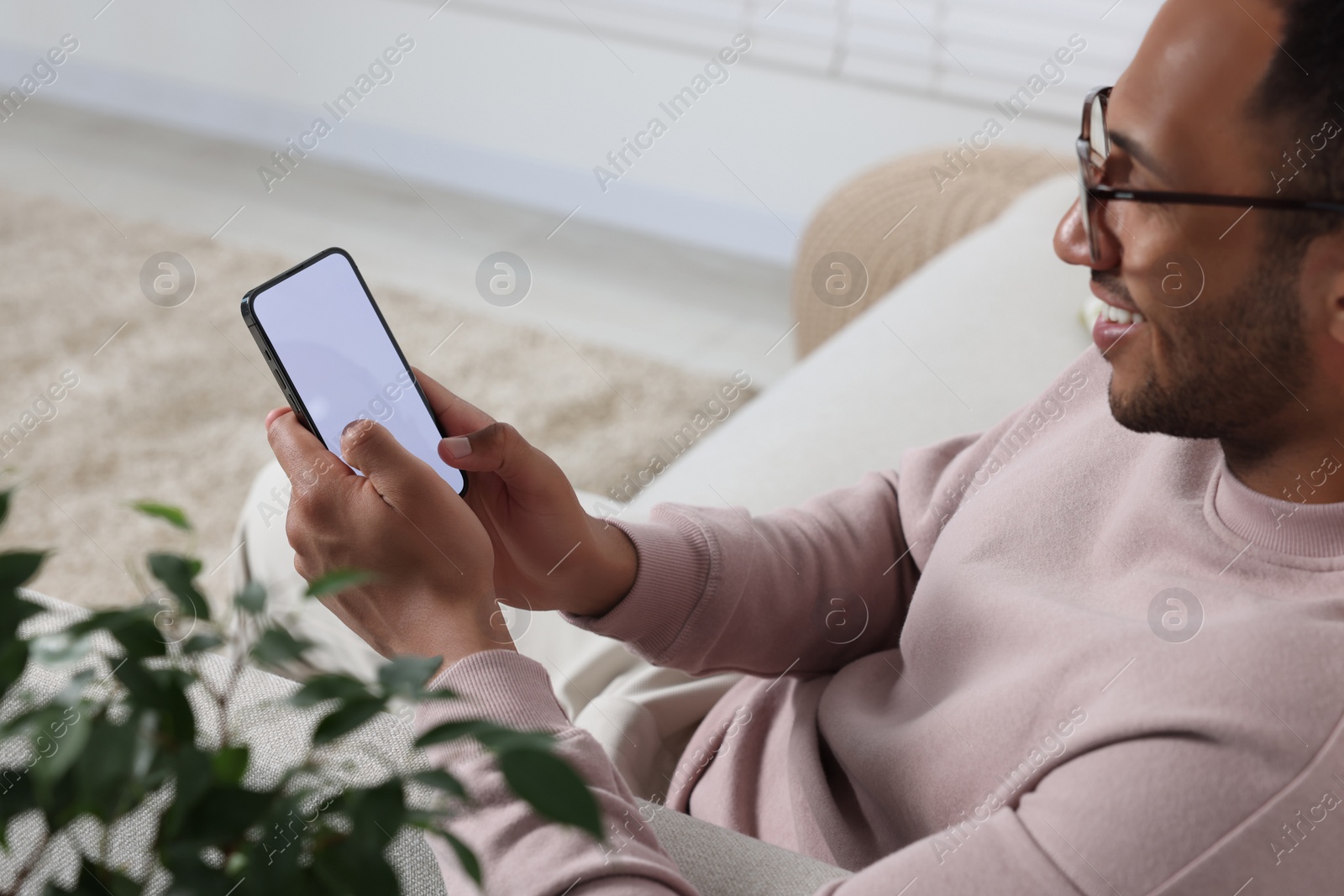 Photo of Man using modern mobile phone at home, selective focus