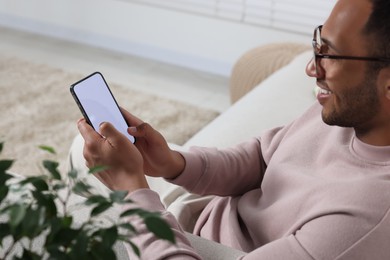 Man using modern mobile phone at home, selective focus