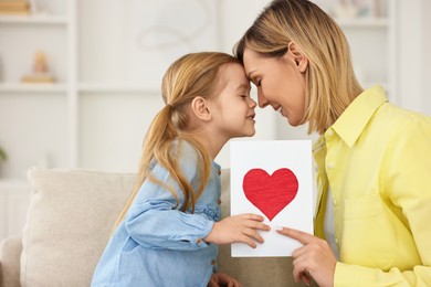 Photo of Little daughter congratulating her mom with greeting card at home, space for text. Happy Mother's Day