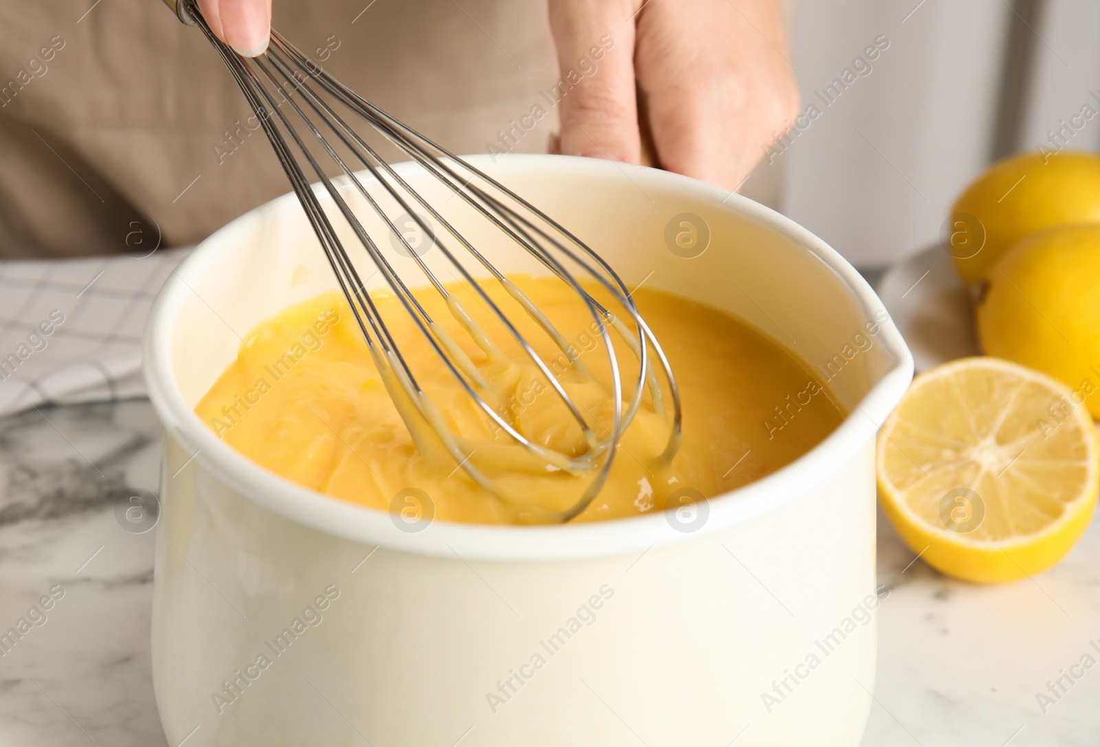 Photo of Woman cooking delicious lemon curd at white marble table, closeup