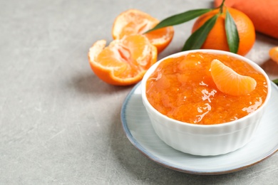 Delicious tangerine jam on light grey table. Space for text