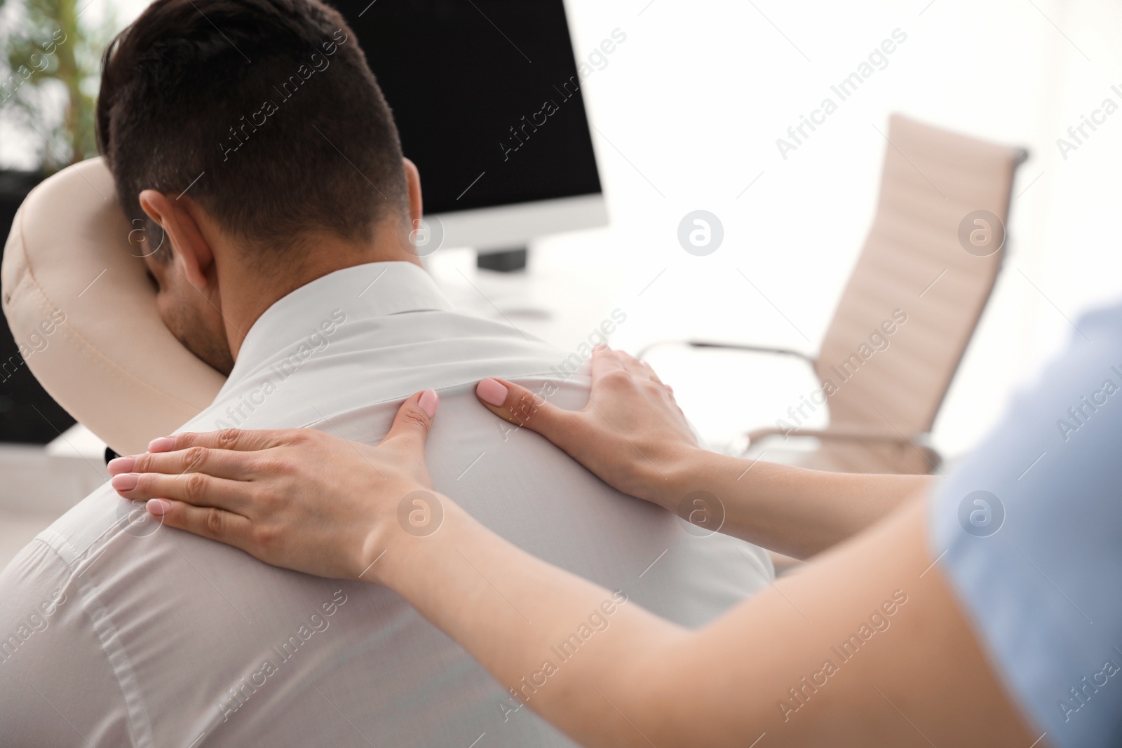 Photo of Man receiving massage in modern chair indoors, closeup