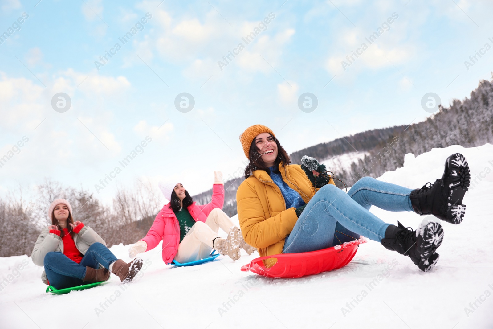 Photo of Group of friends having fun and sledding on snow. Winter vacation