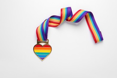 Photo of Rainbow ribbon with heart pendant on white background, top view. LGBT pride