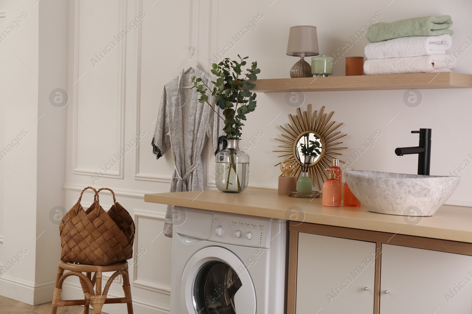 Photo of Laundry room interior with modern washing machine and stylish vessel sink on countertop